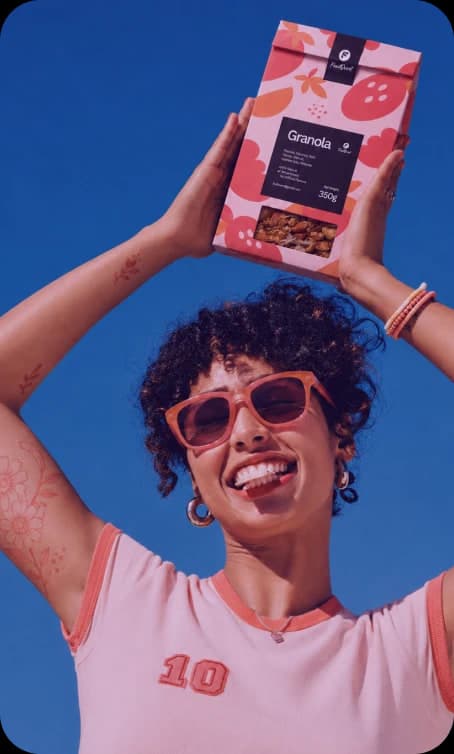 Woman in red sunglasses holding a Fruitvent granola box overhead