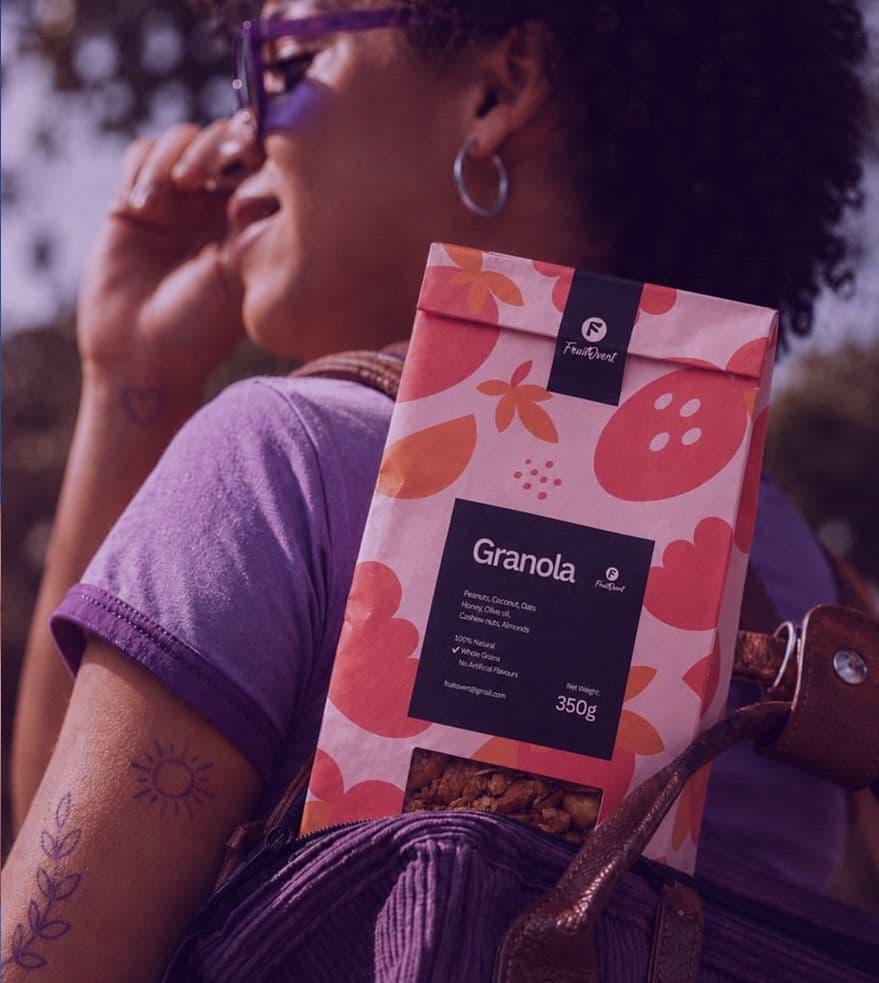 A woman in purple glasses with a FruitOvert granola pack in her backpack